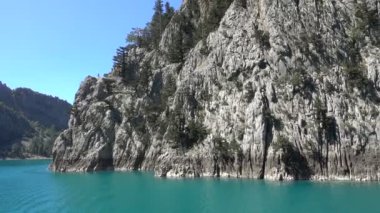Oimapinar Barajı 'nın çevresindeki dağ kayalıkları arasında bir gölde seyreden bir tekne görüntüsü. Yeşil Kanyon, Manavgat, Antalya, Türkiye