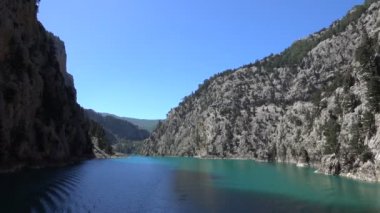 Oimapinar Barajı 'nın çevresindeki dağ kayalıkları arasında bir gölde seyreden bir tekne görüntüsü. Yeşil Kanyon, Manavgat, Antalya, Türkiye