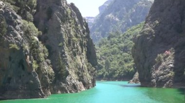 Oimapinar Barajı 'nın çevresindeki dağ kayalıkları arasında bir gölde seyreden bir tekne görüntüsü. Yeşil Kanyon, Manavgat, Antalya, Türkiye