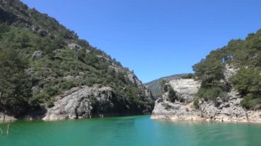 Oimapinar Barajı 'nın çevresindeki dağ kayalıkları arasında bir gölde seyreden bir tekne görüntüsü. Yeşil Kanyon, Manavgat, Antalya, Türkiye