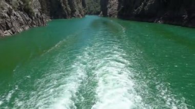 Oimapinar Barajı 'nın çevresindeki dağ kayalıkları arasında bir gölde seyreden bir tekne görüntüsü. Yeşil Kanyon, Manavgat, Antalya, Türkiye