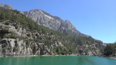 Oimapinar Barajı 'nın çevresindeki dağ kayalıkları arasında bir gölde seyreden bir tekne görüntüsü. Yeşil Kanyon, Manavgat, Antalya, Türkiye