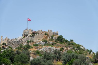 Kalekoy, Simena, Türkiye - 3 Haziran 2019: Türkiye 'nin batık Kekova kenti yakınlarındaki Uchagiz körfezindeki tepenin üzerine taş evler ve şato inşa edilmiş Kalekoy köyü