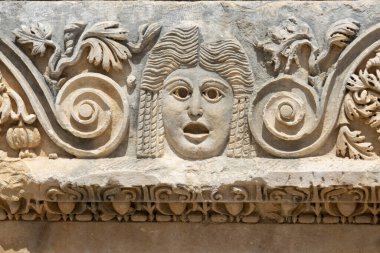 Türkiye 'nin Antalya ilinin Demre kentindeki antik Myra kentindeki Greko-Romen amfitiyatrosunun taş maskelerinin görüntüsü ön cephede.