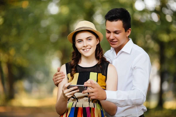 Glada unga älskande par står utomhus tillsammans och tittar på mobiltelefonen tillsammans — Stockfoto