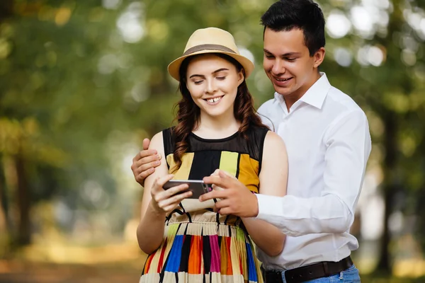 Feliz joven pareja amorosa de pie al aire libre juntos y mirando el teléfono móvil juntos — Foto de Stock