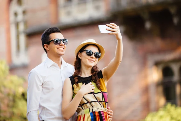 快乐年轻爱夫妇站在户外一起和看着手机在一起 — 图库照片