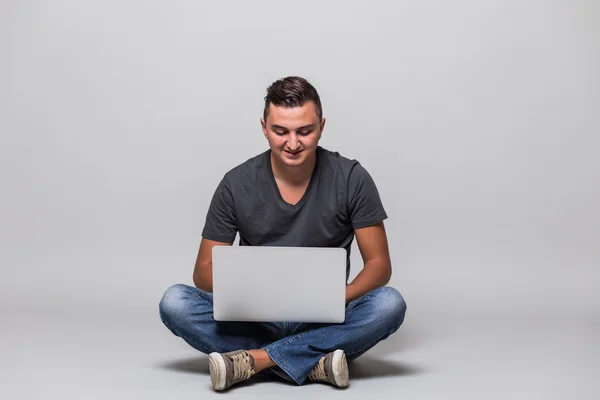 Hombre casual feliz sentado en el suelo con el ordenador portátil — Foto de Stock