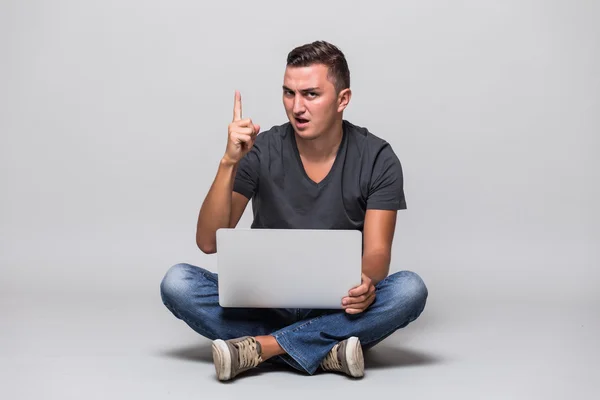 Hombre casual en camiseta blanca sentado en el suelo con el ordenador portátil y el dedo hacia arriba — Foto de Stock