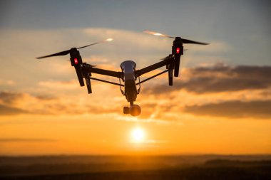 quadrocopter drone with remote control. Dark silhouette against colorfull sunset. clipart