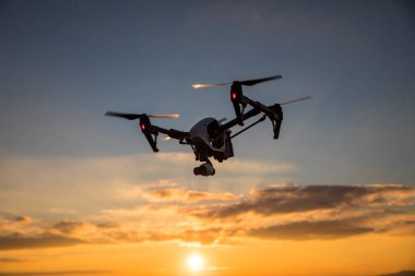 Uzaktan kumanda ile quadrocopter dron. Derma günbatımı karşı karanlık siluet.