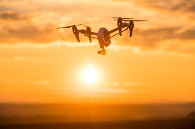 Uzaktan kumanda ile quadrocopter dron. Derma günbatımı karşı karanlık siluet.