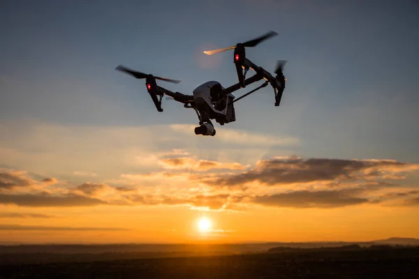 Drone quadrocopter con telecomando. Silhouette scura contro il tramonto colorato . — Foto Stock