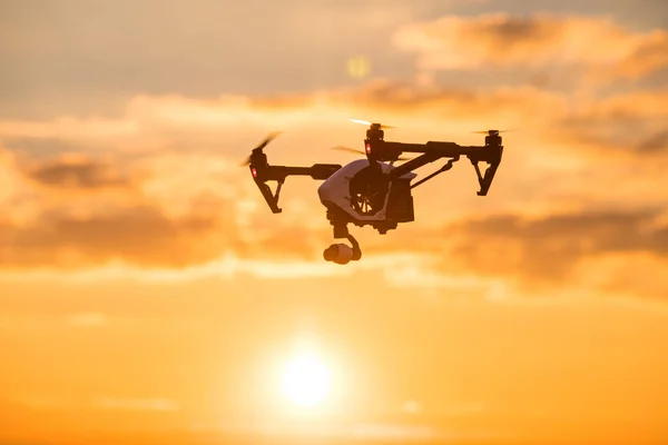 Quadrocopter drone med fjärrkontroll. Mörk siluett mot colorfull sunset. — Stockfoto