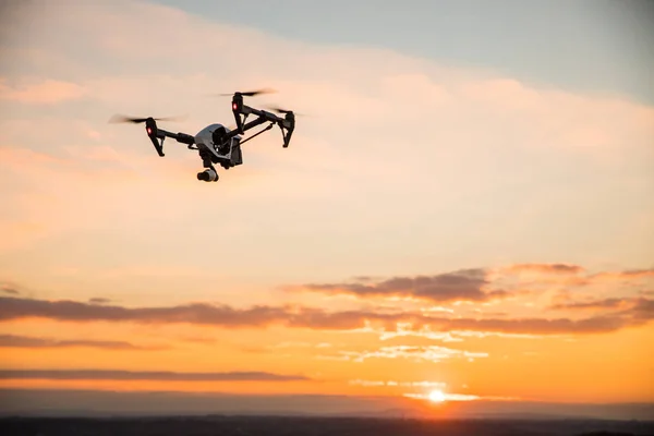 Quadrocopter drone med fjärrkontroll. Mörk siluett mot colorfull sunset. — Stockfoto