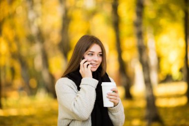 Kız konuşmak telefon ile kahve güneşli sarı Park
