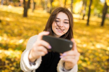 Güneşli sonbahar Park cep telefonunda selfie alarak bir gülücük ver