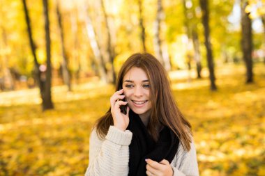 Güneşli sonbahar Park telefonda konuşmak kız portresi