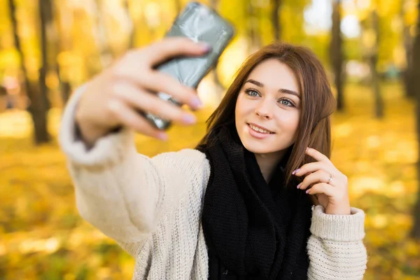 Smile girl taking selfie on mobile phone in sunny autumn park — Stock Photo, Image