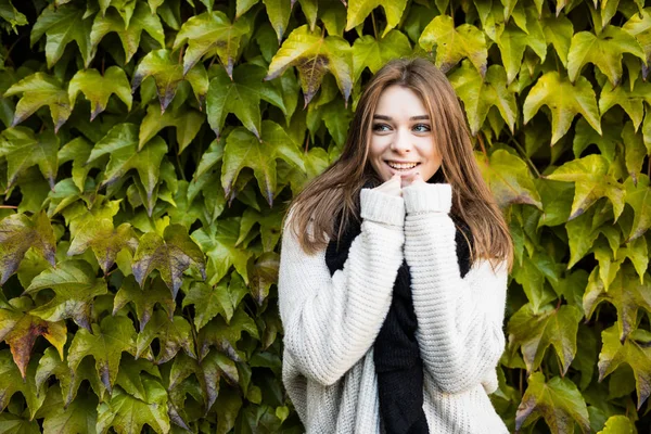 Portré fiatal szépség barna lány kint hideg, zöld levelek háttér — Stock Fotó