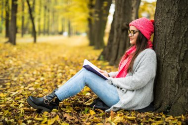 esmer düşmüş bir sonbahar üzerinde oturan bir kitap okuma bir parkta bırakır