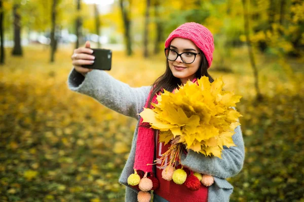 Junge Frau mit Herbstblättern vor Selfie — Stockfoto