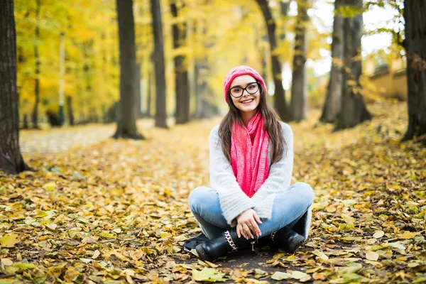 Mädchen sitzt im gelben Herbstpark — Stockfoto