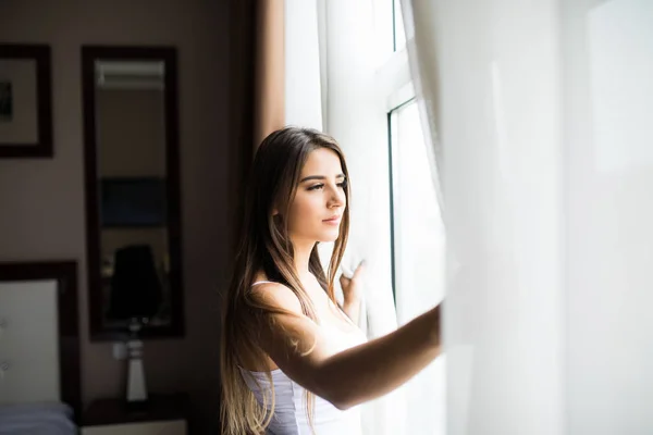 Mulher abertura cortinas de janela — Fotografia de Stock