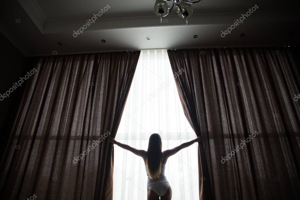  Girl is opening curtains and meeting sunrise