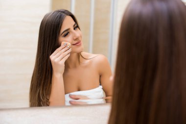 evde aynaya bakarak ve yüzünde krem uygulamak kadın