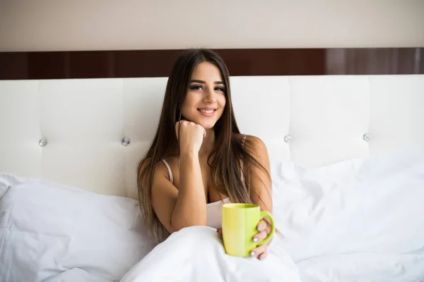 Yatakta otururken kahve içme kadın — Stok fotoğraf