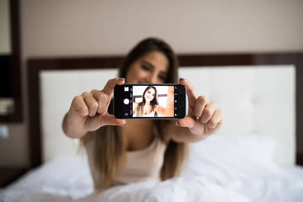 Flicka gör selfie i sängen — Stockfoto