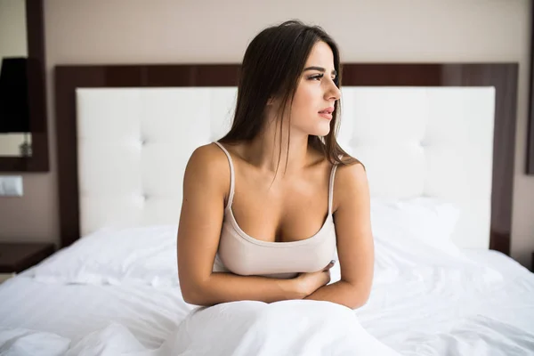 Жінка сидить на ліжку з болем — стокове фото