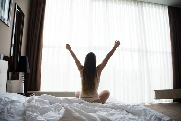 Mulher esticando na cama depois de acordar — Fotografia de Stock
