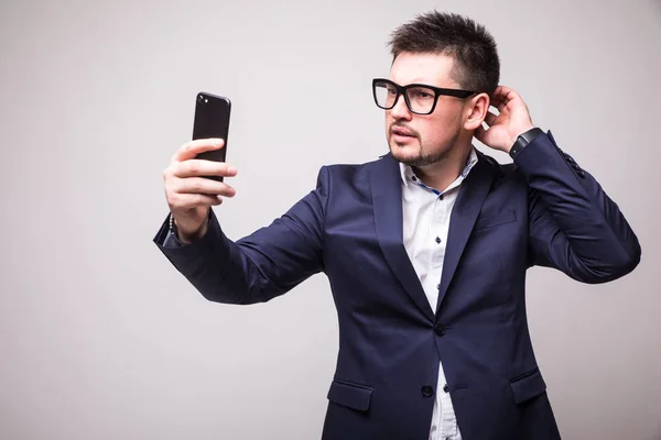 İzole telefonu beyaz arka plan seyir takım elbiseli genç adam — Stok fotoğraf