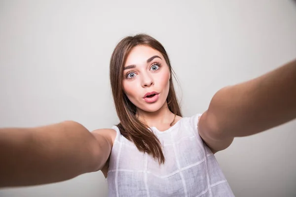 Young girl making selfie  on a gray background — Stock Photo, Image