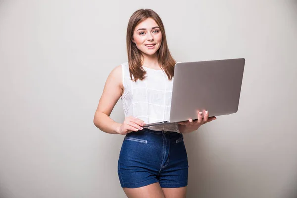 Lány állt, és használ a laptop felső szürke háttér — Stock Fotó