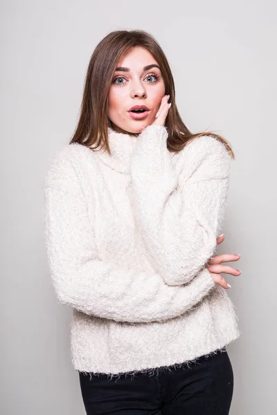 Шокированная девушка в свитере на изолированном сером фоне студии — стоковое фото