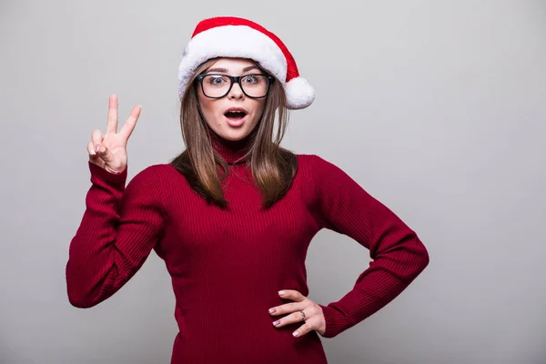 Menina de Natal saiu com o dedo do Papai Noel para cima em fundo cinza — Fotografia de Stock