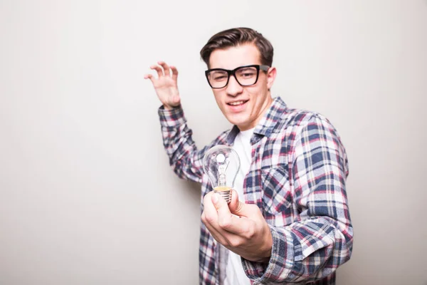 Jovem homem em óculos segurando pequena lâmpada — Fotografia de Stock