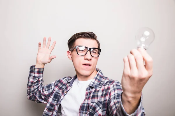 Jovem homem em óculos segurando pequena lâmpada — Fotografia de Stock