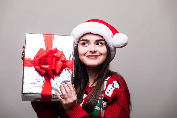 Mujer con caja de regalo. Hermosa morena chica usando en suéter y sombrero de Santa aislado . — Foto de Stock