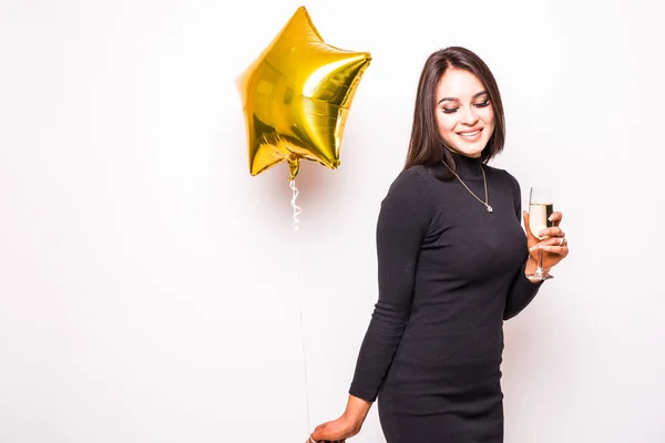 Mooie jonge vrouw in zwarte jurk met gouden ster vormige ballon glimlachend en drinken champagne — Stockfoto