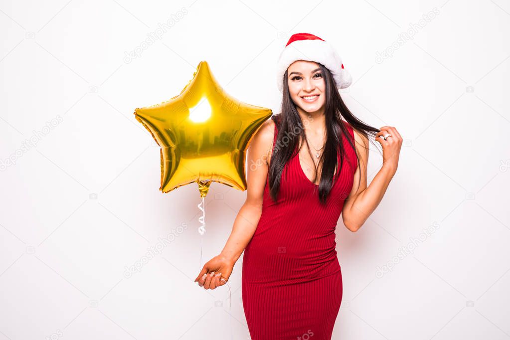 Pretty young woman in red dress and santa christmas hat with gold star shaped balloon 