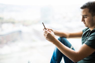 Genç adam panoramik penceresinde telefon kullanma