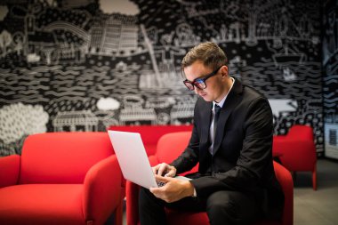 Ofiste otururken dizüstü bilgisayarda çalışma gözlük kendine güvenen genç adam yan görünüm