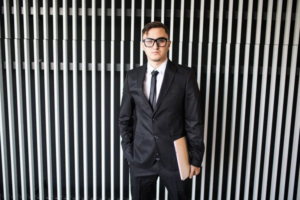 オフィスの壁に対してスーツの青年実業家 — ストック写真