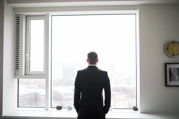 Jeune homme d'affaires regarder par la fenêtre à son bureau — Photo