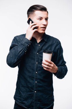 Sıradan kıyafetler giyen genç bir adam cep telefonuyla konuşuyor.