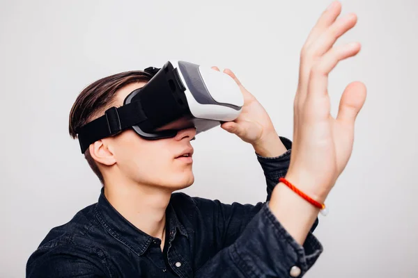 Ung hane spela videospel med virtuell verklighet headset och joystick eller köra med fjärrkontroll. — Stockfoto